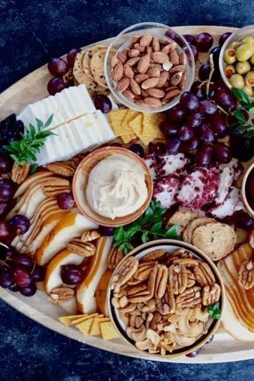 Charcuterie tray with party food like nuts, crackers, fruit, olives, and cheese