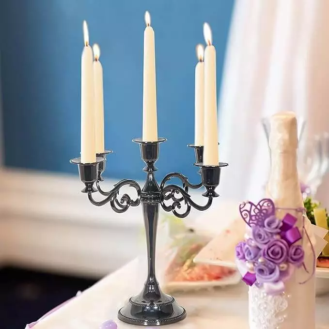Black Candelabra With White Candles Sitting On A Table Near A Vase With Purple Flowers